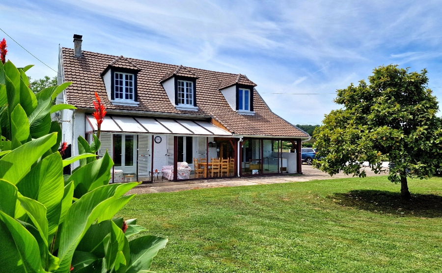 Modern take on the French longère with front awning, outdoor seating and white windows