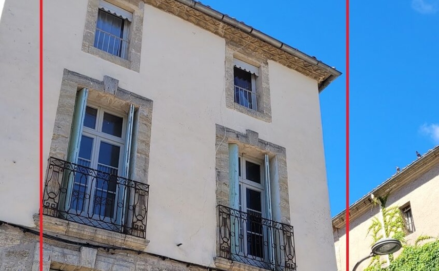 A classic apartment building in the Hérault with blue shutters on the windows and wrought iron gates