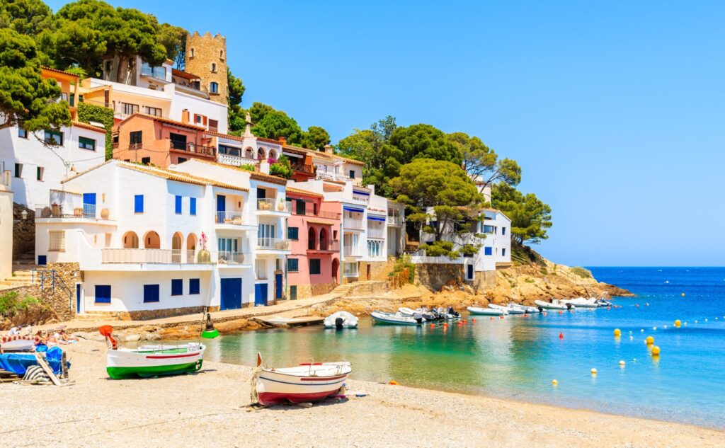 Fishing boats on beach in Sa Tuna village with colorful houses on shore, Costa Brava, Catalonia, Spain